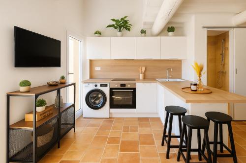 a kitchen with white cabinets and a counter with stools at Le Nily Provence, douceur & vue d'exception in Sainte-Tulle