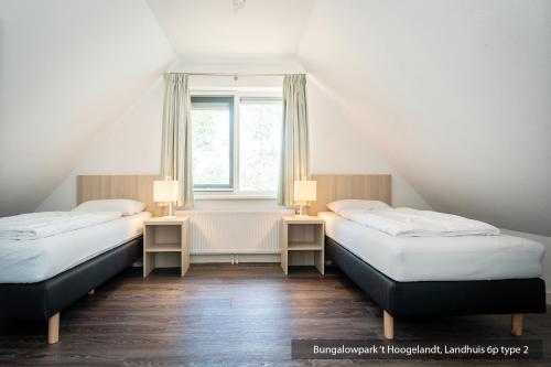 two beds in a room with a window at Bungalowpark 't Hoogelandt in De Koog