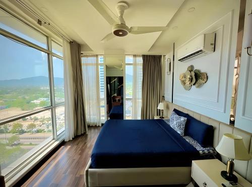 een slaapkamer met een blauw bed en een groot raam bij Executive Prestige Hotel Apartments Facing Centautus - Elysium Tower Islamabad in Islamabad