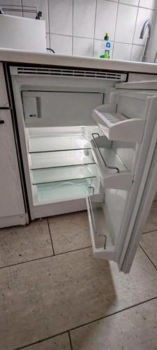 an empty refrigerator with its door open in a kitchen at Ankerplatz Lichtblick in Travemünde