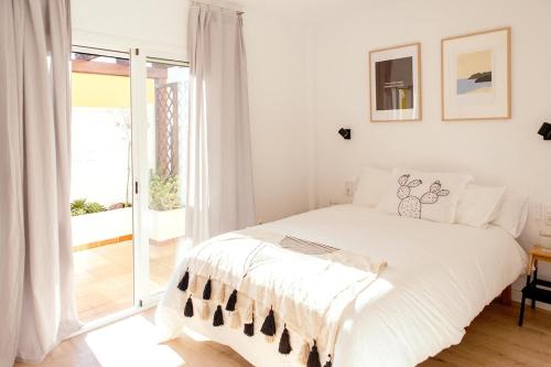 a white bedroom with a bed and a sliding glass door at ZURIA - Casa tranquila con patio en Cabo de Gata in El Pozo de los Frailes