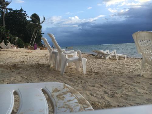 a row of white chairs on the beach at Jungle Hut Bungalows & Hotel in Haad Chao Phao