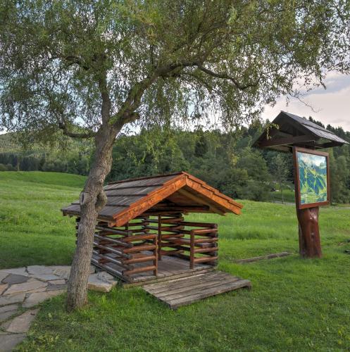 a wooden structure next to a tree in a field at Motel Skalka in Radola