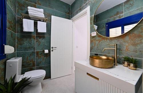 a bathroom with a sink and a toilet and a mirror at אחוזת סנטוריני - וילה מהממת עם בריכה מחוממת וג'קוזי בעין יעקב in ‘Ein Ya‘aqov