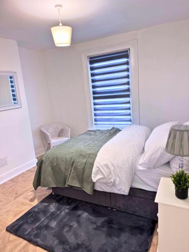a white bedroom with a bed and a window at House for 8 in Gillingham close to train station with free parking in Gillingham
