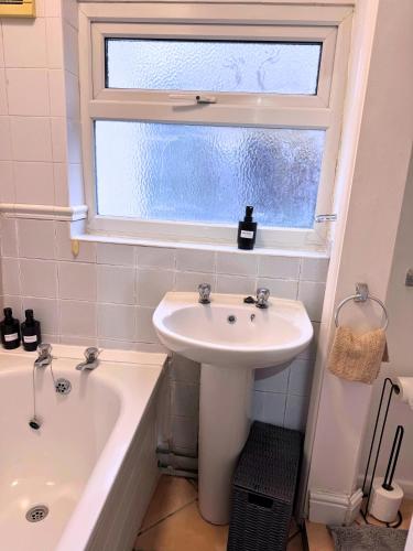 a bathroom with a sink and a tub and a window at House for 8 in Gillingham close to train station with free parking in Gillingham