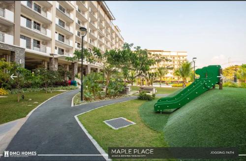 a playground with a green slide in a park at Staycacia Haven 2BR Condo Maple Acacia Taguig in Manila