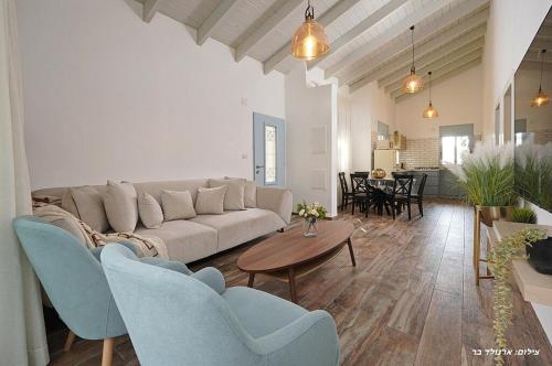 Mashabbe Sadeにあるהילת השחר - וילה מדהימה עם 3 חדרי שינה ובריכה פרטית מחוממת ומקורה בעין יעקבのソファとテーブルと椅子のあるリビングルーム