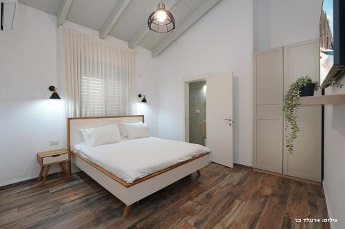 a bedroom with a bed in a white room at הילת השחר - וילה מדהימה עם 3 חדרי שינה ובריכה פרטית בעין יעקב in Mashabbe Sade