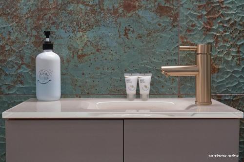 a bottle of alcohol sitting on a bathroom sink at הילת השחר - וילה מדהימה עם 3 חדרי שינה ובריכה פרטית בעין יעקב in Mashabbe Sade