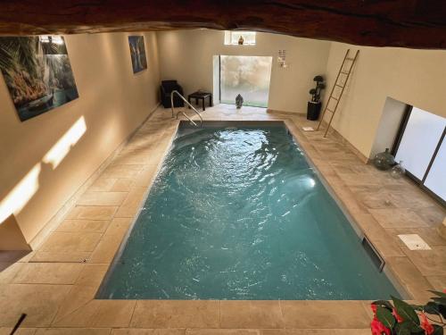 an indoor swimming pool with green water in a house at Mon Petit Paradis avec Piscine Intérieure Privative Chauffée et climatisation in Lournand