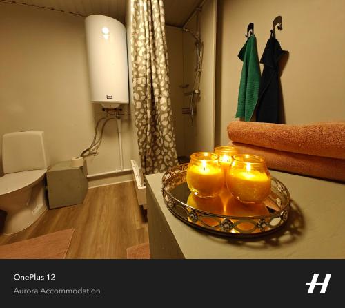 een badkamer met drie kaarsen op een bord op een aanrecht bij Aurora Lakeside Cabin Altajärvi in Kiruna