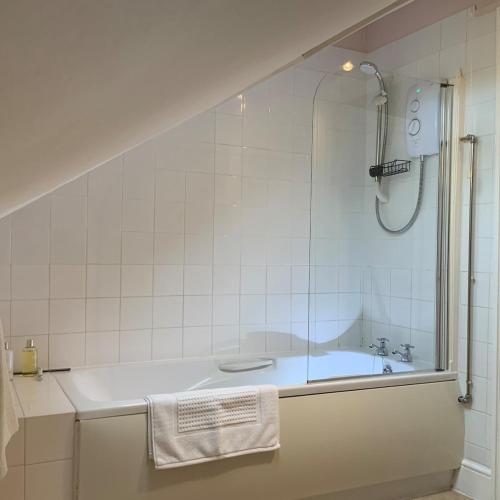 a white bathroom with a tub and a shower at Large 2 bedroom town centre top floor flat with free parking in Dorchester