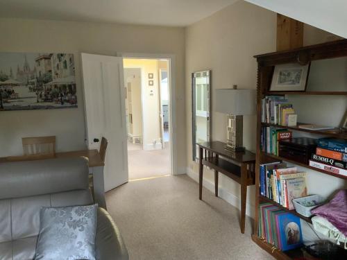a living room with a couch and a book shelf with books at Large 2 bedroom town centre top floor flat with free parking in Dorchester
