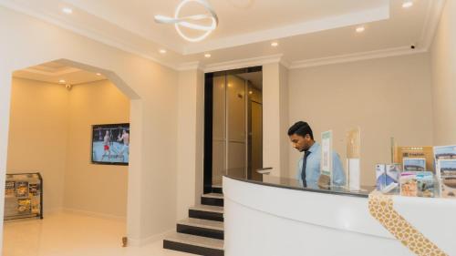 Een man aan een toonbank in een winkel. bij PAN Hotel Apartments in Sharjah