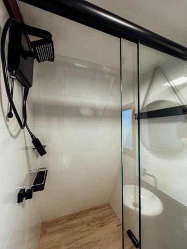 a bathroom with a toilet and a glass shower stall at Chalé mirante do Sol in Socorro