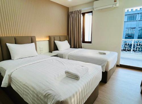 a hotel room with two beds and a window at Excel Hotel Bangkok former Sri Krungthep Hotel in Bangkok