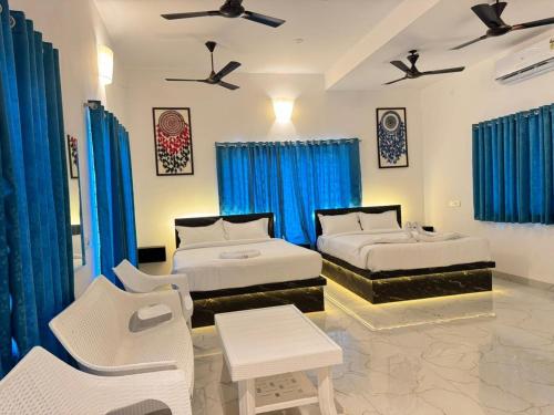 2 camas en una habitación con cortinas azules en La Coromandel Luxury - TIE, en Pondicherry