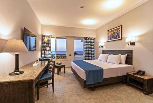 Invidia Coral Beach Tiran في شرم الشيخ: غرفة فندق بها سرير ومكتب ونافذة