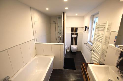 a bathroom with two sinks and a tub and a toilet at Ferienhaus Weideblick in Hymendorf