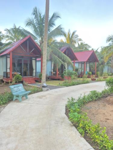 a bench in front of a building with palm trees at Homestay Xóm Quê in Ấp Thành Hòa