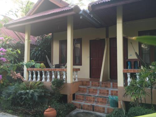 a house with a porch and a fence at Jungle Hut Bungalows & Hotel in Haad Chao Phao