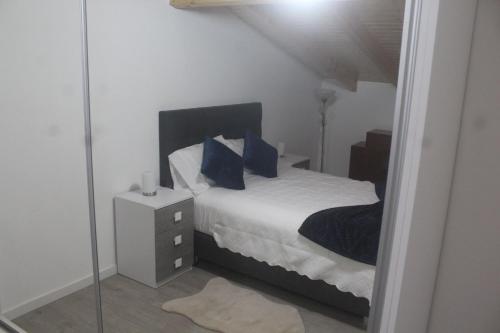 una camera da letto con letto, cuscini blu e specchio di Casa da Quinta a Estreito da Calheta
