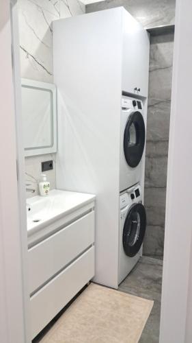 ein weißes Badezimmer mit einer Waschmaschine und einem Waschbecken in der Unterkunft Уютный Дом in Chişinău