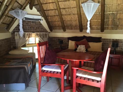 a room with a table and chairs and a bed at Big Tuskers Bush Camp in Marloth Park