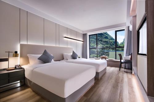 een witte slaapkamer met twee bedden en een raam bij 妙酒店阳朔西街漓江店 in Yangshuo