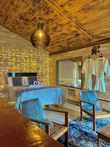 1 Schlafzimmer mit einem Bett, 2 Stühlen und einem Spiegel in der Unterkunft Quiosque Família Chalé Beija-Flor in Joanópolis