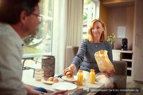 a woman sitting at a table with a man eating food at Vakantiepark De Krim Texel in De Cocksdorp