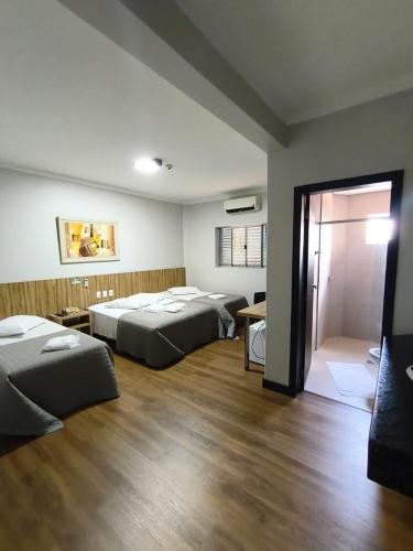 a bedroom with two beds and a sliding door at Hotel Talismã in Rondonópolis