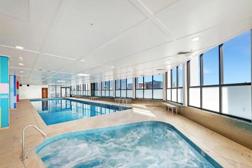 a large swimming pool in a building with windows at Meriton Parramatta in Sydney