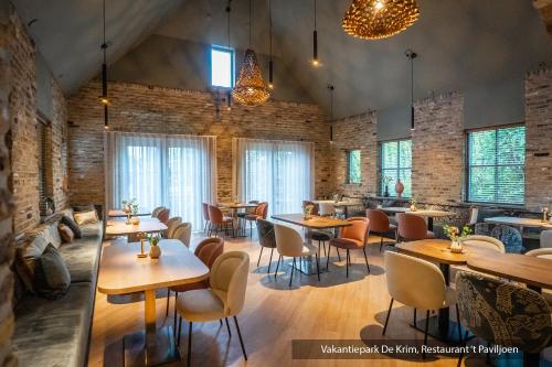 a restaurant with tables and chairs and windows at Villapark Residentie Texel in De Cocksdorp