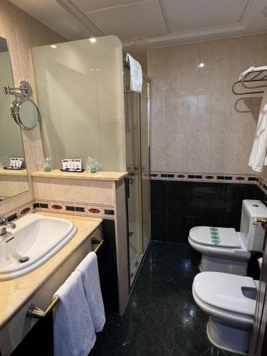 a bathroom with a sink and a toilet and a shower at Hotel El Cisne - parking exterior gratuito in Zaragoza