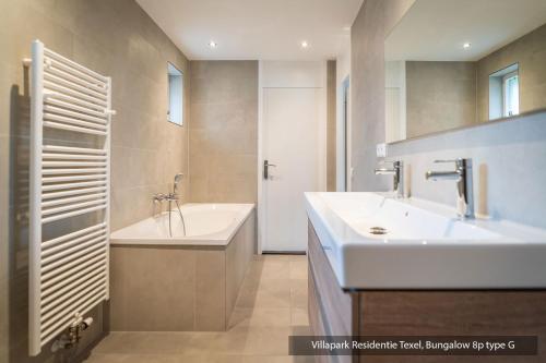 un baño con lavabo y bañera en Villapark Residentie Texel, en De Cocksdorp