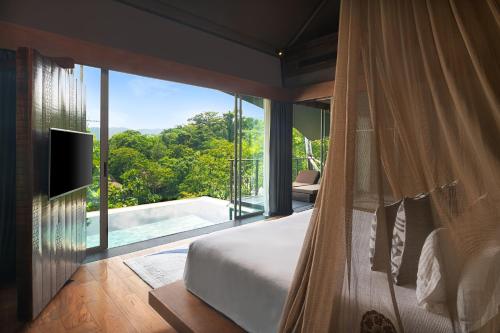 a bedroom with a bed and a view of a pool at Keemala in Kamala Beach