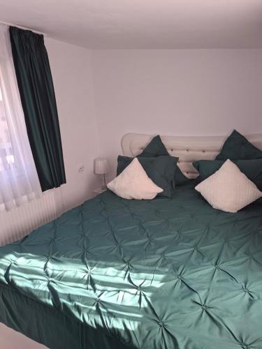 a bedroom with a bed with green sheets and pillows at Casuța Râului in Zărneşti