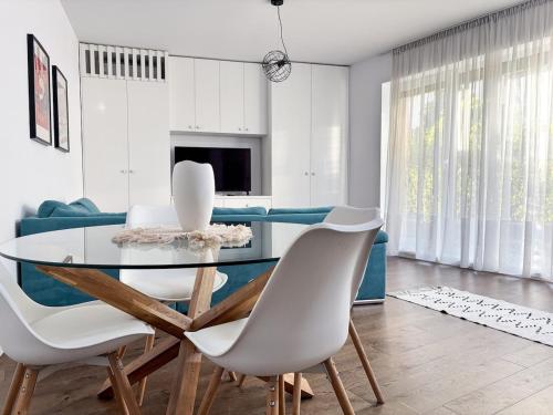 a dining room with a glass table and white chairs at Sunshine Luxury Apartment Private Parking in Cluj-Napoca