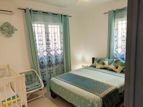 a bedroom with a bed and a chair and windows at Coconut Palm Retreat in Flic-en-Flac