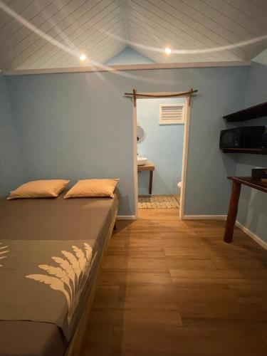 um quarto com uma cama e uma porta para um banheiro em Tetaha Lodge em Tiputa