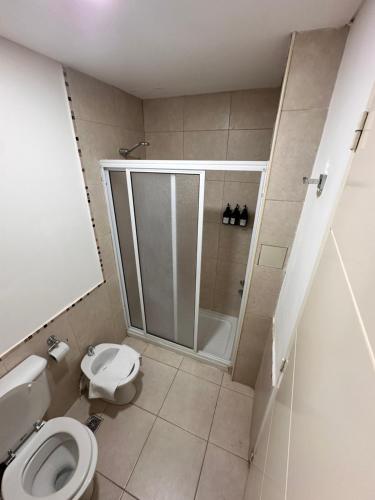 a bathroom with a shower and a toilet in it at Belgrano Apart in Comodoro Rivadavia