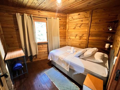 a bedroom with a bed in a wooden cabin at Cabana Betari - Petar in Iporanga