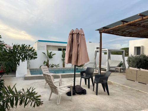 een patio met stoelen en een parasol naast een zwembad bij Casa Wechi in Willemstad