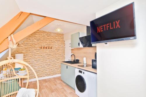 a kitchen with a microwave and a tv on a wall at NOUVEAU BOHEME STUDIO - Netflix & Clim - Centre Ville Transports - Idéal PRO ou COUPLE - Cosy & Confort - NEUF & OFFRE SPÉCIALE in Saint-Omer