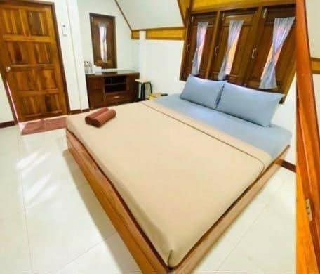 Un dormitorio con una cama con marco de madera. en Koh Libong Maldives Homestay, 