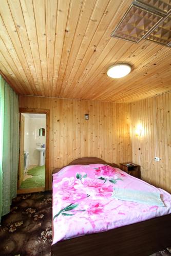 a bedroom with a bed with pink sheets and a ceiling at Еко-садиба "Під ліском" in Yablunytsya