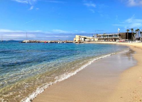 Una playa con el océano y edificios al fondo. en Escapade à Bandol balcon verdoyant et plage à deux pas, en Bandol
