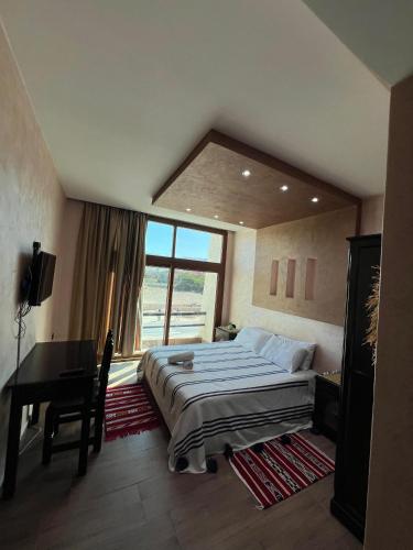 a bedroom with a bed and a desk and a window at Nomad Surf Hotel in Tamraght Ouzdar
